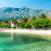 Valkoinen hiekkaranta kirkkaalla vedellä, palmuja, punakattoisia taloja ja vuori taustalla Orebicissa, Kroatiassa